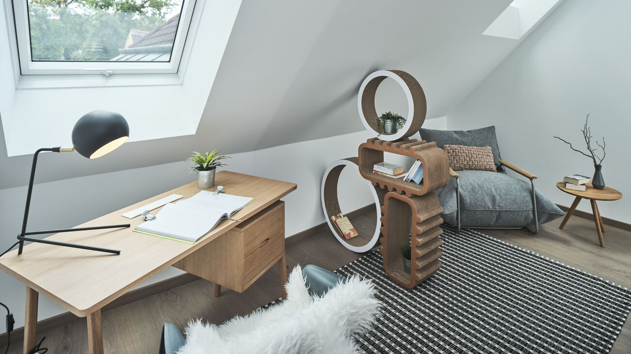 Mini-HomeOffice: Eichenschreibtisch mit Lade, schwarze Tischleuchte, weißer Kunststoffstuhl mit Fell, Pappregale, grauer Aufblas-Design-Lounger mit Filzbezug, grauer Teppich, Beistelltisch Eiche mit Vase und Zweigen