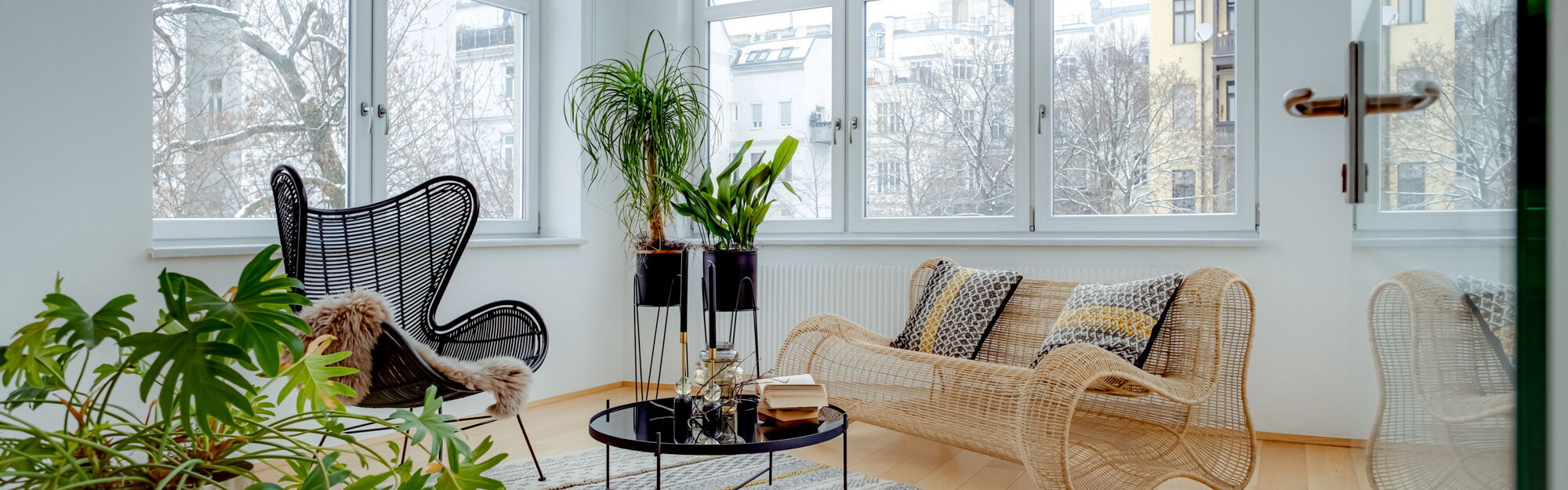 Wintergarten mit Seilsofa, Teppich und vielen Pflanzen in Metalltöpfen