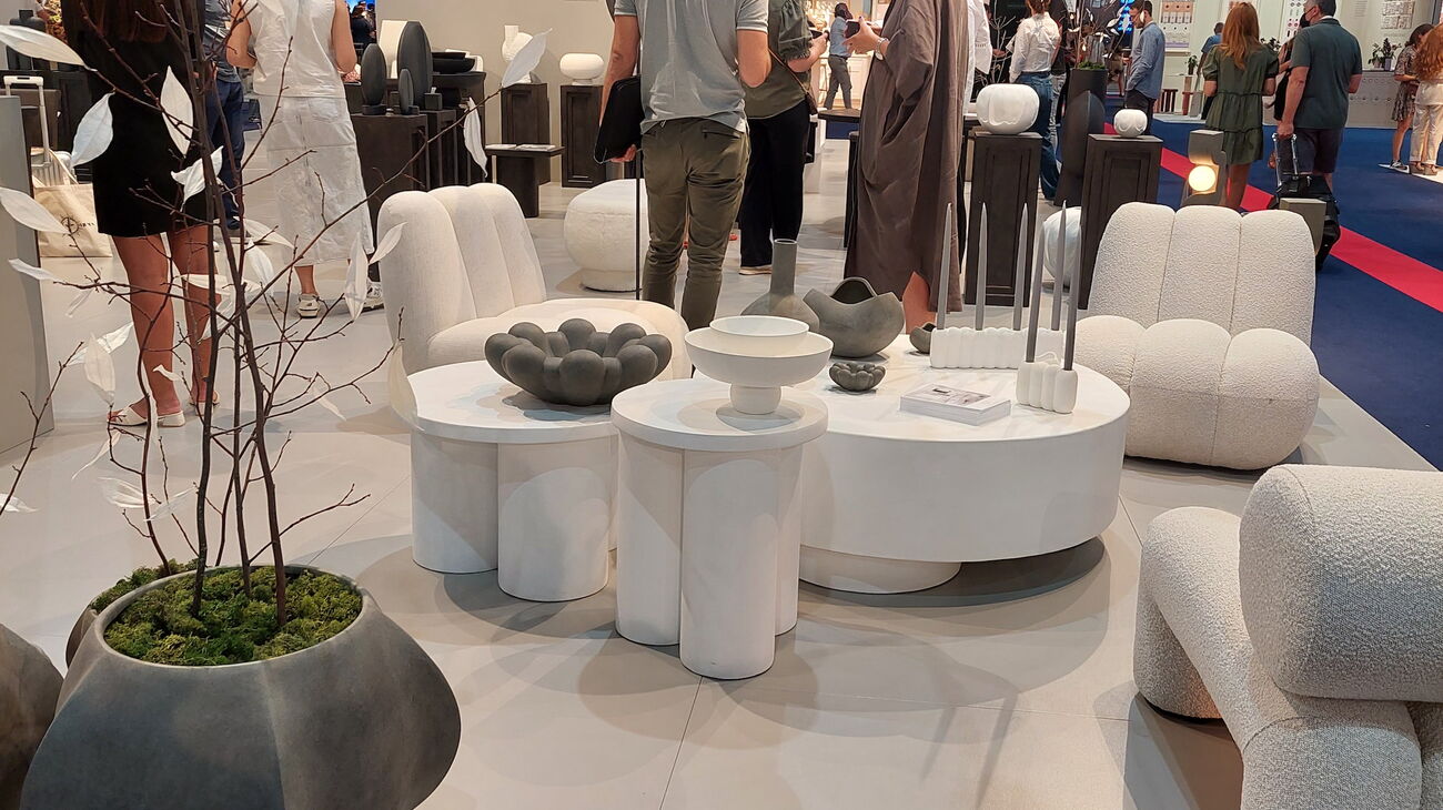 großer Messestand von 101 Copenhagen mit schwarzen mehrarmigen Deckenleuchten aus Metall und großen, gemütlichen Sofalandschaften in creme