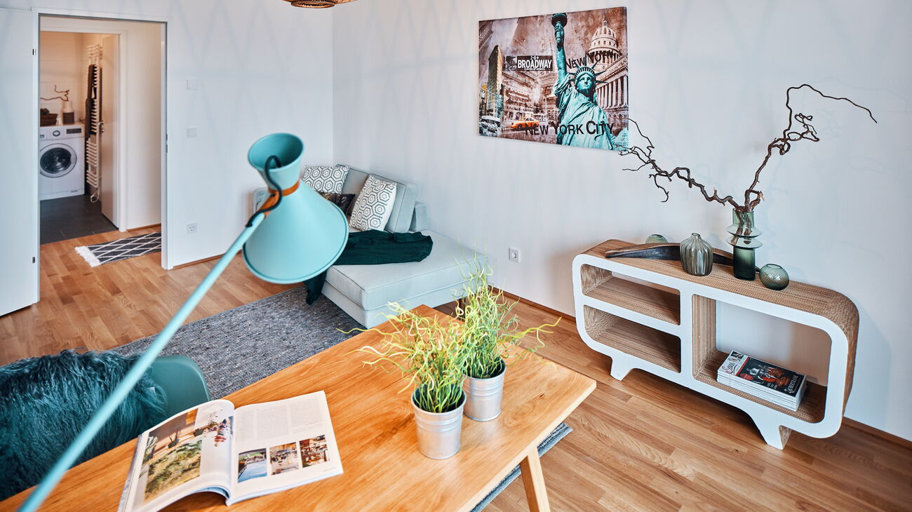 Home Office mit Eichenschreibtisch, mintfarbener Schreibtischleuchte, Sideboard aus Pappe und mintgrünem Sofa sowie modernem NewYork Bild und Rattanhängeleuchte oval