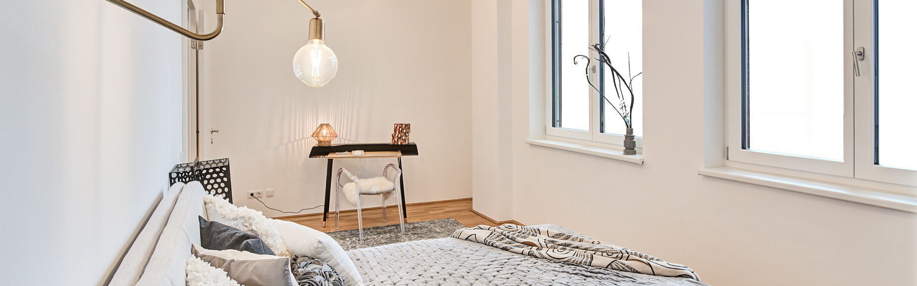 Boxspringbett in grau mit Tagesdecke und mit Leseleuchte an der Wand in Gold