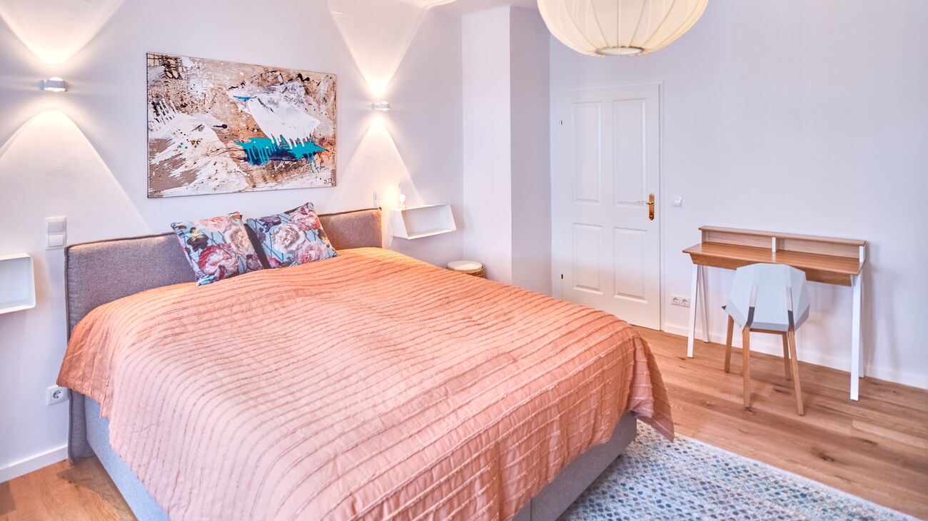 Boxspringbett, Schreibtisch mit Stuhl, Wandregalen, Wandleuchten und moderner Kunst