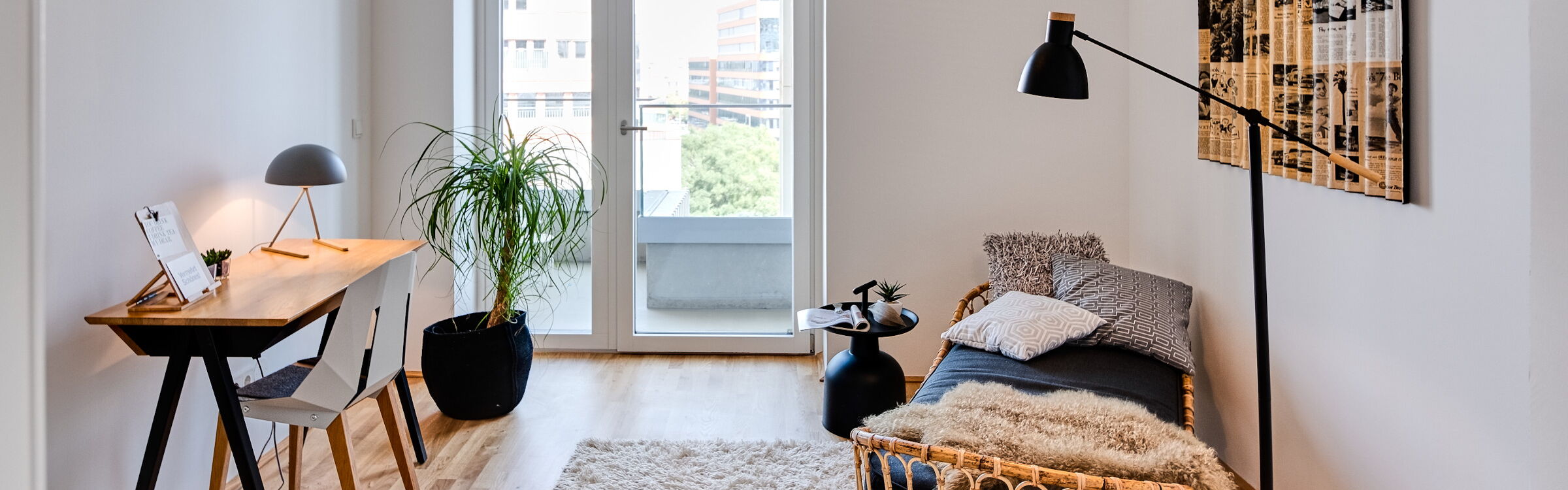 kleiner Holzschreibtisch mit Stuhl, Teppich und Rattan-Gästebett mit Stehleuchte