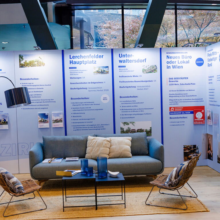 Gemütliches Skandi-Sofa in blaugrau, Sisalteppich, Rattan-Lounger, schwarze Bogenleuchte, Couchtisch in schwarz und bunte Deko-Kissen