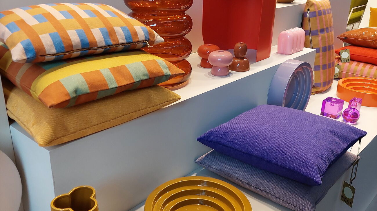 Arrangement aus Kissen und Geschirr in kräftigen Orange, Senf- und Violett-Tönen