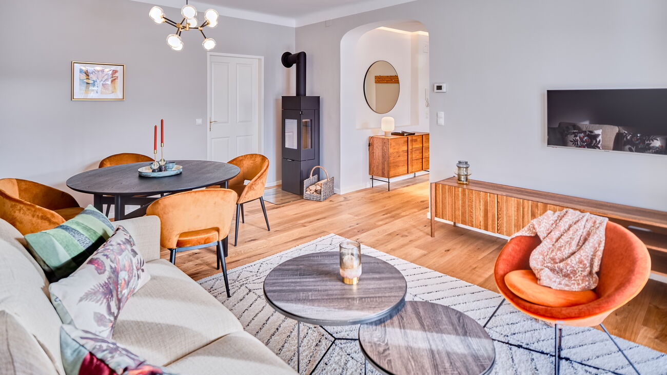 Wohnzimmer mit Schlafsofa, TV Board, Esstisch, Stühlen und Holzofen